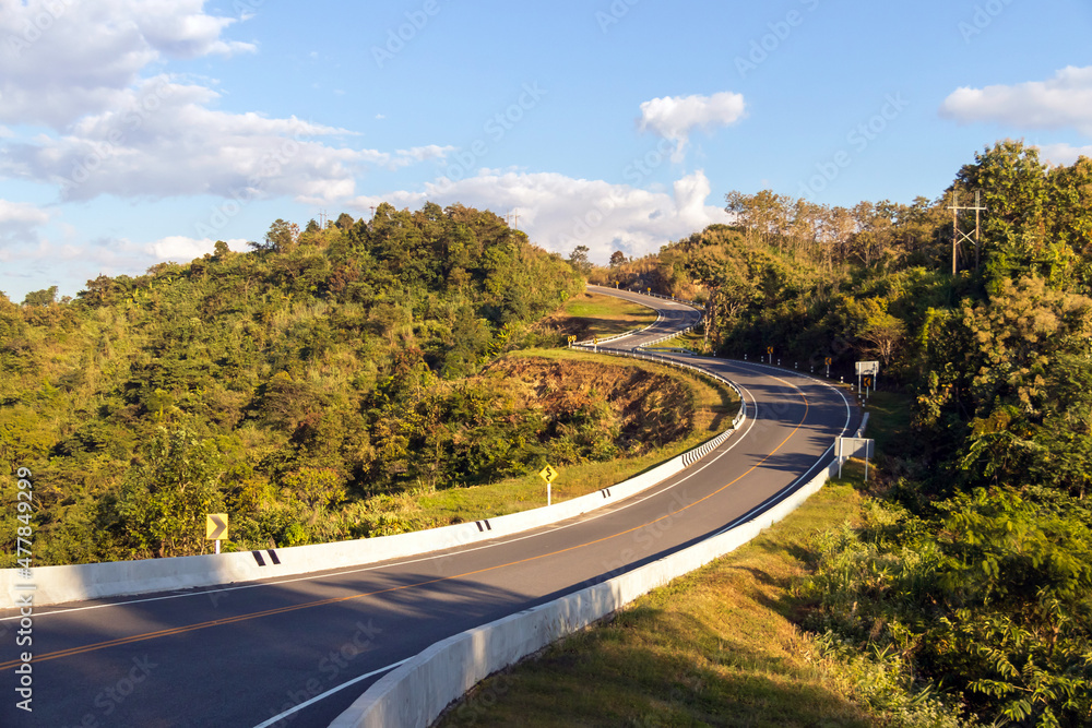 Fototapeta premium Curve road No. 3, or sky road on Root 1081 over top of mountains with green jungle in Santisuk - Bo Kluea District. Beautiful landscape scenic of road number three at Nan, Thailand.