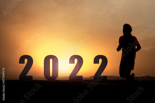 boy running against the light towards some letters with the number of the new year 2022