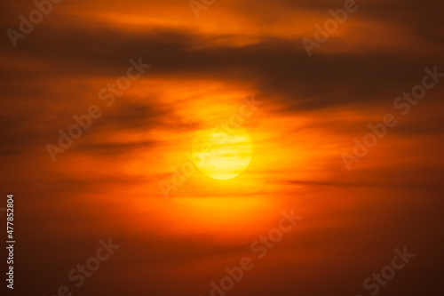 Orange sky and sun shining behind clouds nature background