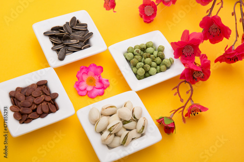 Tet Holiday, Lunar new year, chinese new year concept . Dried sunflower, lotus, watermelon and pumkin seeds top view isolated on yellow. Tet snacks