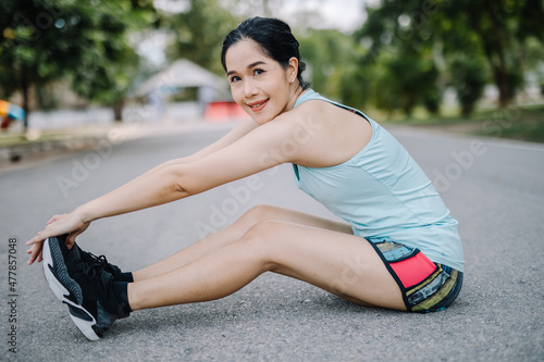 A beautiful woman stretching her body before going for a run in the morning. A female runner kicks her toe to stretch. women's health care concept