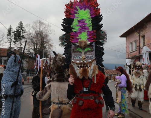 Godech, Bulgaria - January 1, 2022: Mummers in traditional costumes toured the streets of Godech on the first day of 2022. People with a mask called Kukeri dance and perform to scare the evil spirits