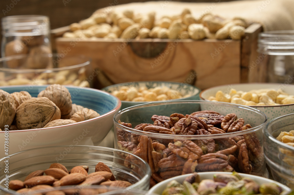 Different nuts and bowls closeup on a wooden table and brown background. Peanut, nut, cashew, almond, hazelnut, pistachio Different nuts and bowls closeup on a wooden table and brown background. Peanut, nut, cashew, almond, hazelnut, pistachio