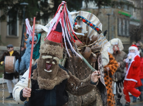Godech, Bulgaria - January 1, 2022: Mummers in traditional costumes toured the streets of Godech on the first day of 2022. People with a mask called Kukeri dance and perform to scare the evil spirits photo