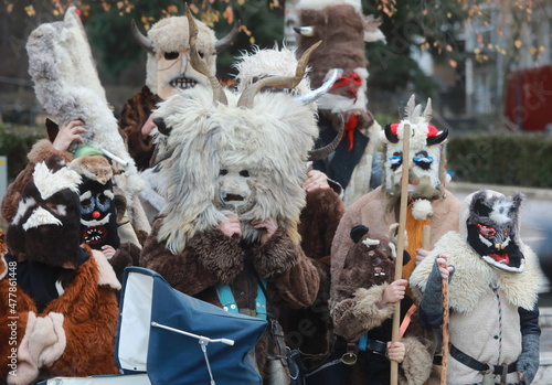 Godech, Bulgaria - January 1, 2022: Mummers in traditional costumes toured the streets of Godech on the first day of 2022. People with a mask called Kukeri dance and perform to scare the evil spirits photo