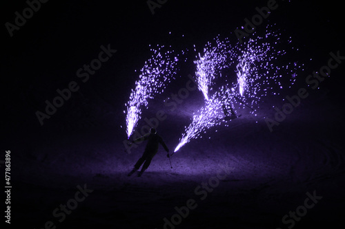 purple fireworks held by skiers at a ski show