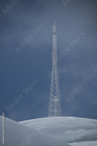 telecommunication tower covered in ice on a snowy mountain