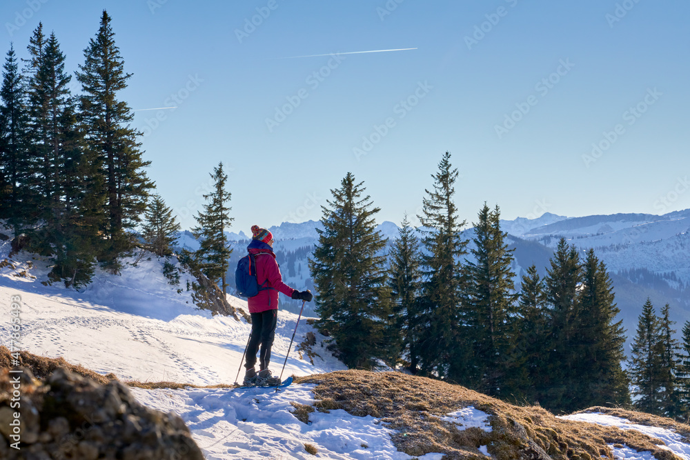 nice and active senior woman snowshoeing in  in the Allgau alps above Immenstadt, Bavaria, Germany 