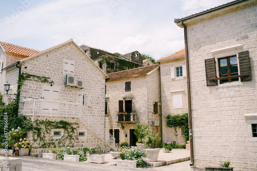 Old stone houses with shutters on the windows and flower beds with greenery in the courtyard