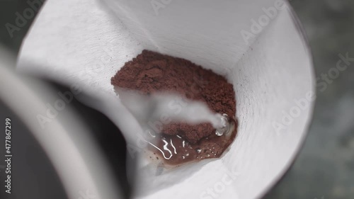 coffee is brewed with hot water from kettle in purover through paper filter. slow motion, close-up view photo
