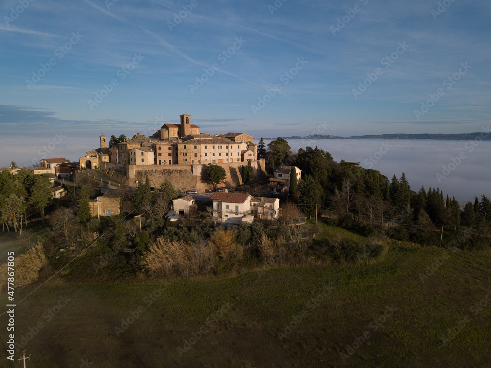 Fototapeta premium aerial view of the medieval village of Piticchio di Arcevia in the province of Ancona in the Marche region of Italy immersed in the fog
