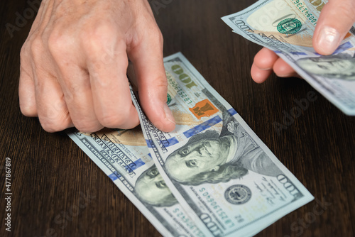 An older woman (old lady) is counting money (dollars). An elderly lady and her hands.