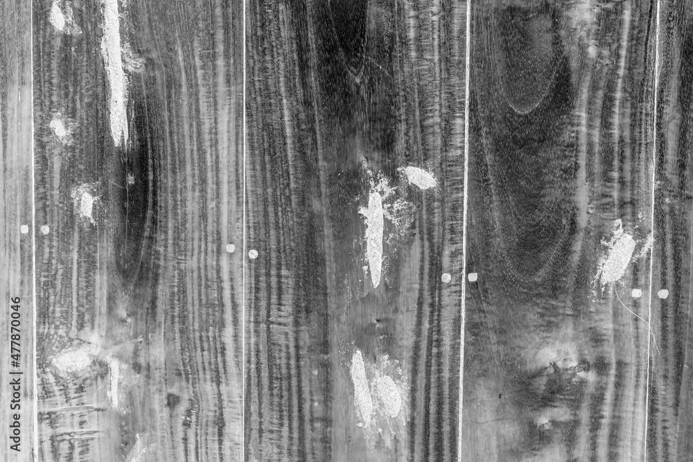 Black and white image of an old wooden board with white repair spots for texture background