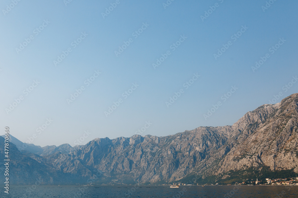Kotor Bay surrounded by mountains in a light haze against a blue sky