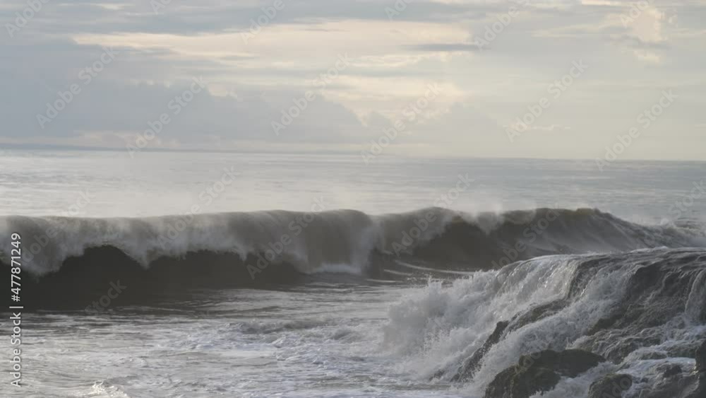 A wonderful evening seascape with a big wave crashing on a dark stone reef. Huge ocean waves break on dark rocks during a big swell. Cloudy sky and golden sunset. Slow motion. 4k A wonderful evening seascape with a big wave crashing on a dark stone reef. Huge ocean waves break on dark rocks during a big swell. Cloudy sky and golden sunset. Slow motion. 4k