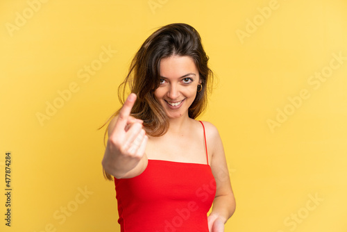 Young caucasian woman isolated on yellow background doing coming gesture