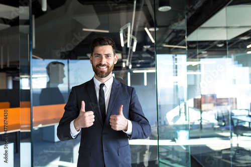 Wallpaper Mural Happy and successful businessman looking at camera and smiling, approvingly showing thumbs up in modern office Torontodigital.ca