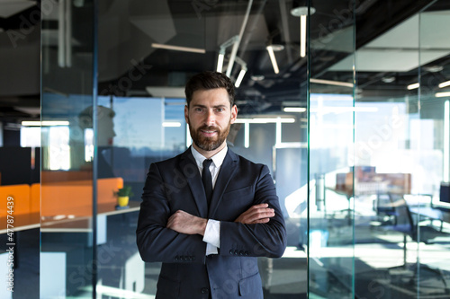 Serious and confident, head businessman with arms crossed, looking at camera, in modern office