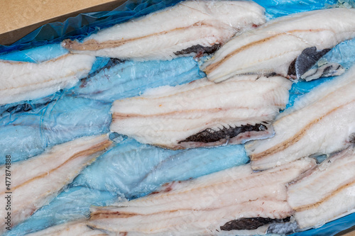 frozen fish Longtail hake in a box. Packaging with interleave plastic film and fish. Argentine commercial fish after primary processing is ready for sale photo