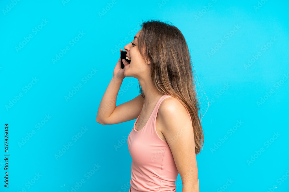 Young caucasian woman using mobile phone isolated on blue background laughing in lateral position Young caucasian woman using mobile phone isolated on blue background laughing in lateral position