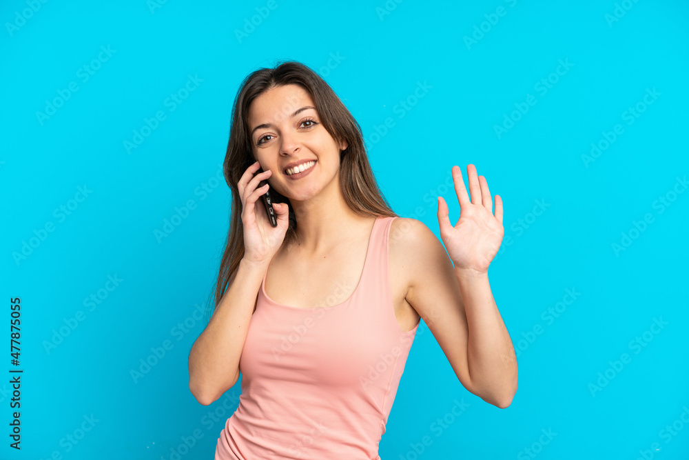 Young caucasian woman using mobile phone isolated on blue background saluting with hand with happy expression Young caucasian woman using mobile phone isolated on blue background saluting with hand with happy expression