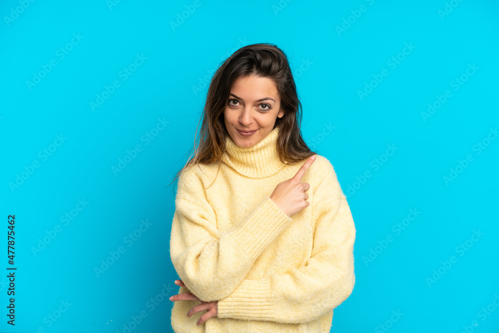 Fototapeta premium Young caucasian woman isolated on blue background pointing to the side to present a product