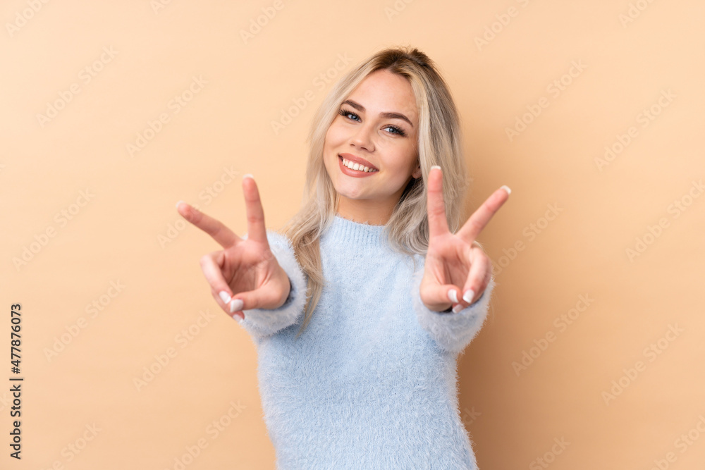 Teenager girl over isolated background smiling and showing victory sign Teenager girl over isolated background smiling and showing victory sign