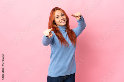 Teenager Russian girl isolated on pink background pointing front with happy expression