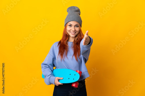 Teenager Russian skater girl isolated on yellow background shaking hands for closing a good deal