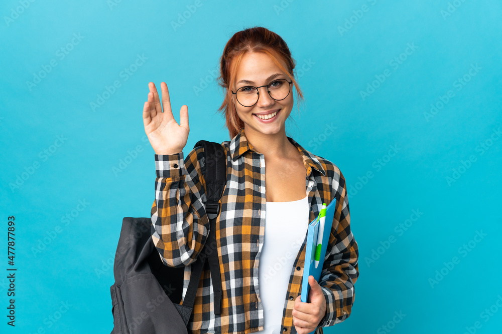 Teenager student Russian girl isolated on blue background saluting with hand with happy expression Teenager student Russian girl isolated on blue background saluting with hand with happy expression