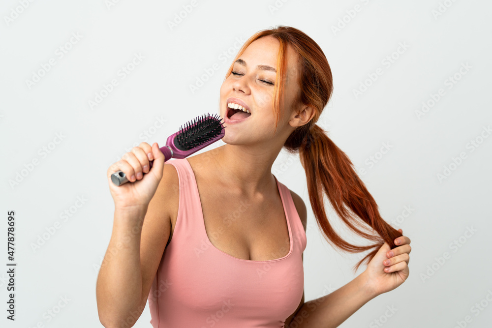 Teenager Russian girl isolated on white background with hair comb and singing Teenager Russian girl isolated on white background with hair comb and singing