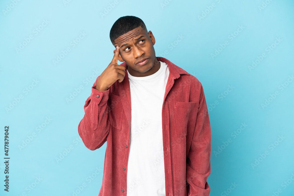 Young latin man isolated on blue background making the gesture of madness putting finger on the head Young latin man isolated on blue background making the gesture of madness putting finger on the head