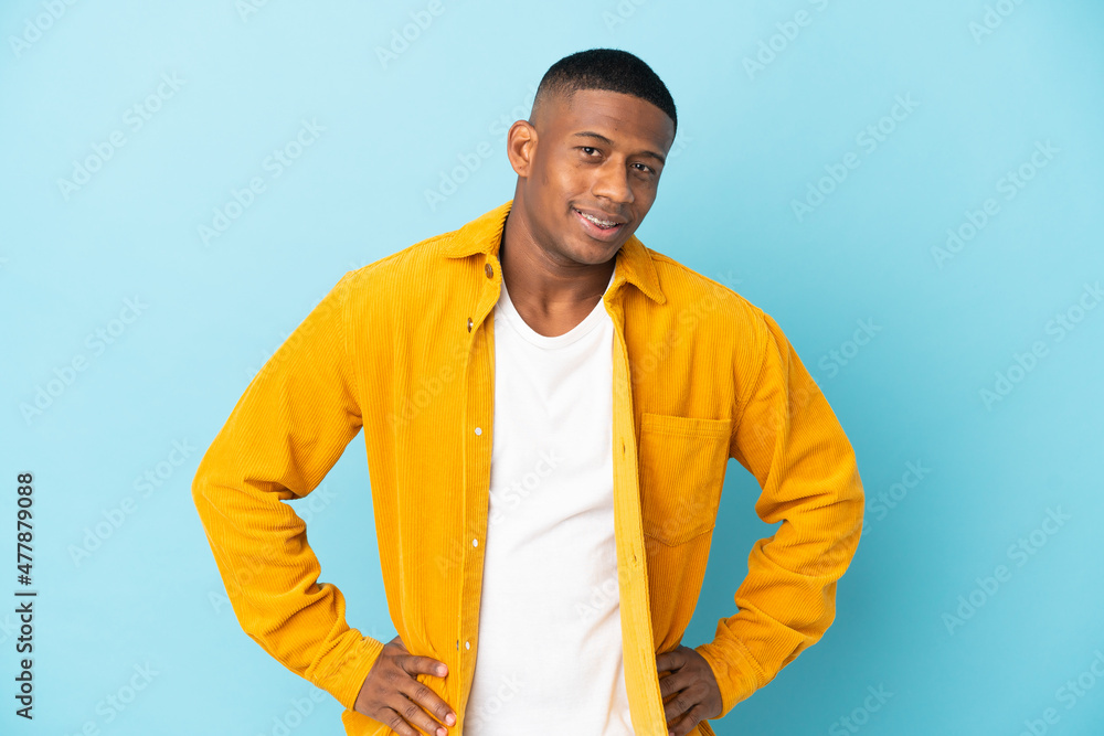 Young latin man isolated on blue background posing with arms at hip and smiling Young latin man isolated on blue background posing with arms at hip and smiling