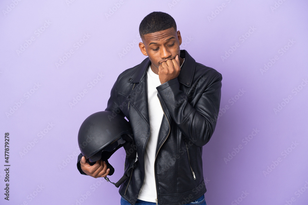 Latin man with a motorcycle helmet isolated on purple background having doubts