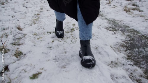 Feet of a woman walking in snow wearing winter shoes. Front view.
