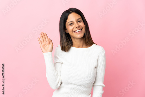 Caucasian girl isolated on pink background saluting with hand with happy expression © luismolinero