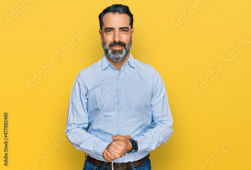 Stampa su tela Middle aged man with beard wearing business shirt with hands together and crossed fingers smiling relaxed and cheerful