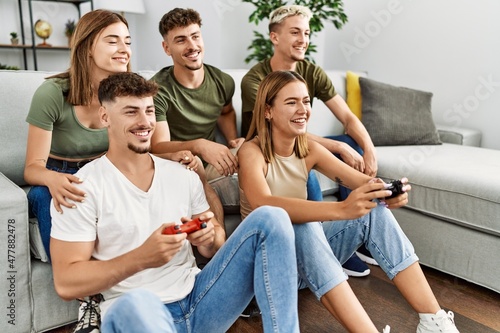 Group of young friends smiling happy playing video game at home.