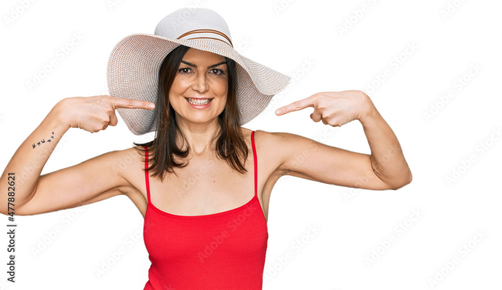 Beautiful brunette woman wearing swimsuit and summer hat smiling cheerful showing and pointing with fingers teeth and mouth. dental health concept. Beautiful brunette woman wearing swimsuit and summer hat smiling cheerful showing and pointing with fingers teeth and mouth. dental health concept.