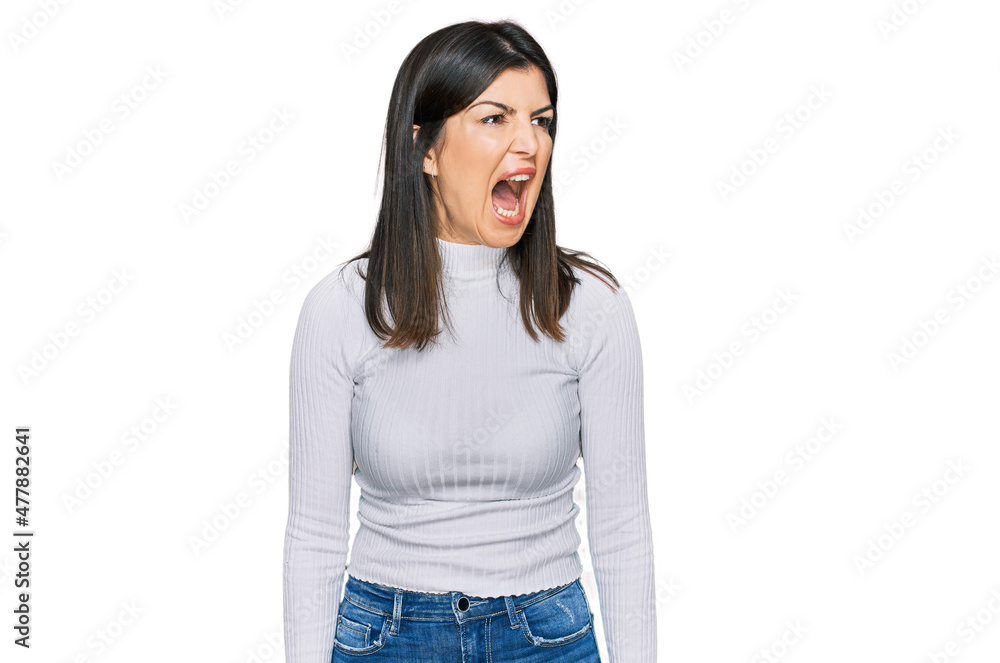 Fototapeta premium Beautiful brunette woman wearing casual clothes angry and mad screaming frustrated and furious, shouting with anger. rage and aggressive concept.
