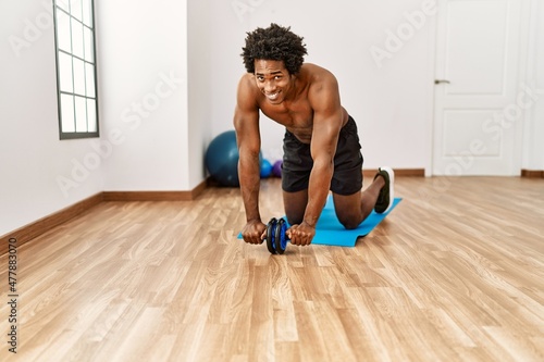 Young african american man training abs using roller at gym