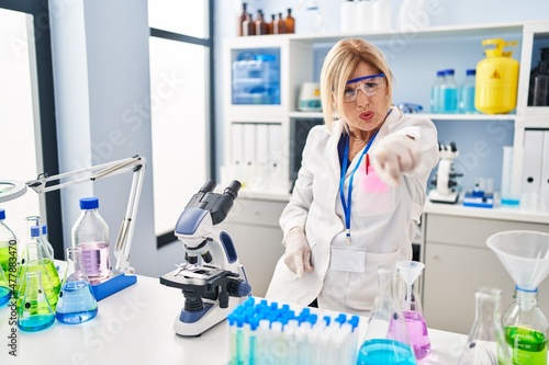Middle age blonde woman working at scientist laboratory pointing displeased and frustrated to the camera  angry and furious with you