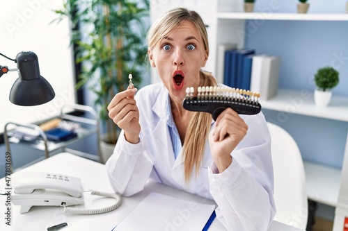 Beautiful dentist woman comparing teeth whitening afraid and shocked with surprise and amazed expression, fear and excited face.