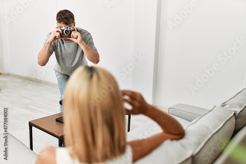 Man making photo to his girlfriend using camera at home.