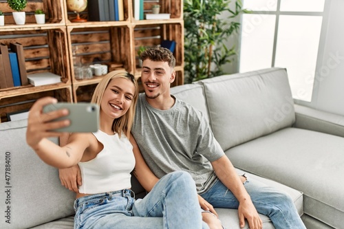 Young caucasian couple smiling happy making selfie by the smartphone at home.
