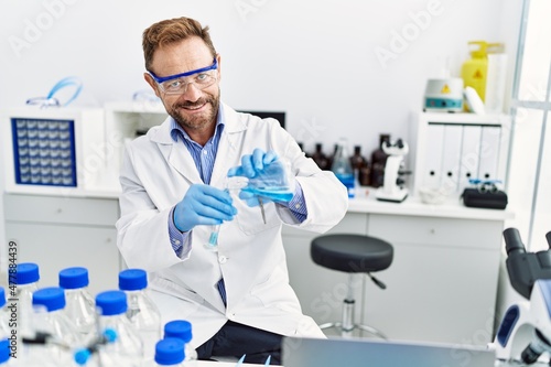 Middle age hispanic man wearing scientist uniform working at laboratory