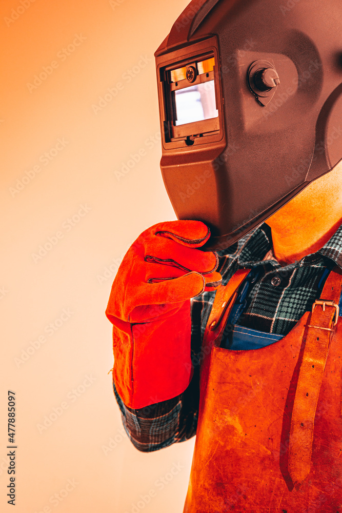Fototapeta premium Heavy industry worker in protective suit with mask to protect eyes and face, vertical photo, close-up, fiery colors