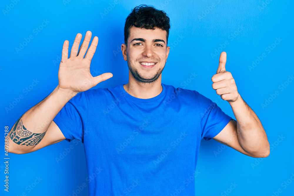 Young hispanic man wearing casual blue t shirt showing and pointing up with fingers number six while smiling confident and happy. Young hispanic man wearing casual blue t shirt showing and pointing up with fingers number six while smiling confident and happy.