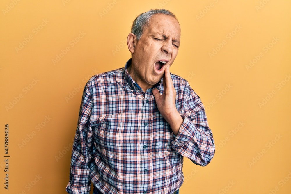 Handsome senior man with grey hair wearing casual shirt touching mouth with hand with painful expression because of toothache or dental illness on teeth. dentist