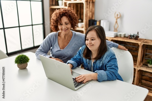 Fotografi Mature mother and down syndrome daughter using computer laptop at home